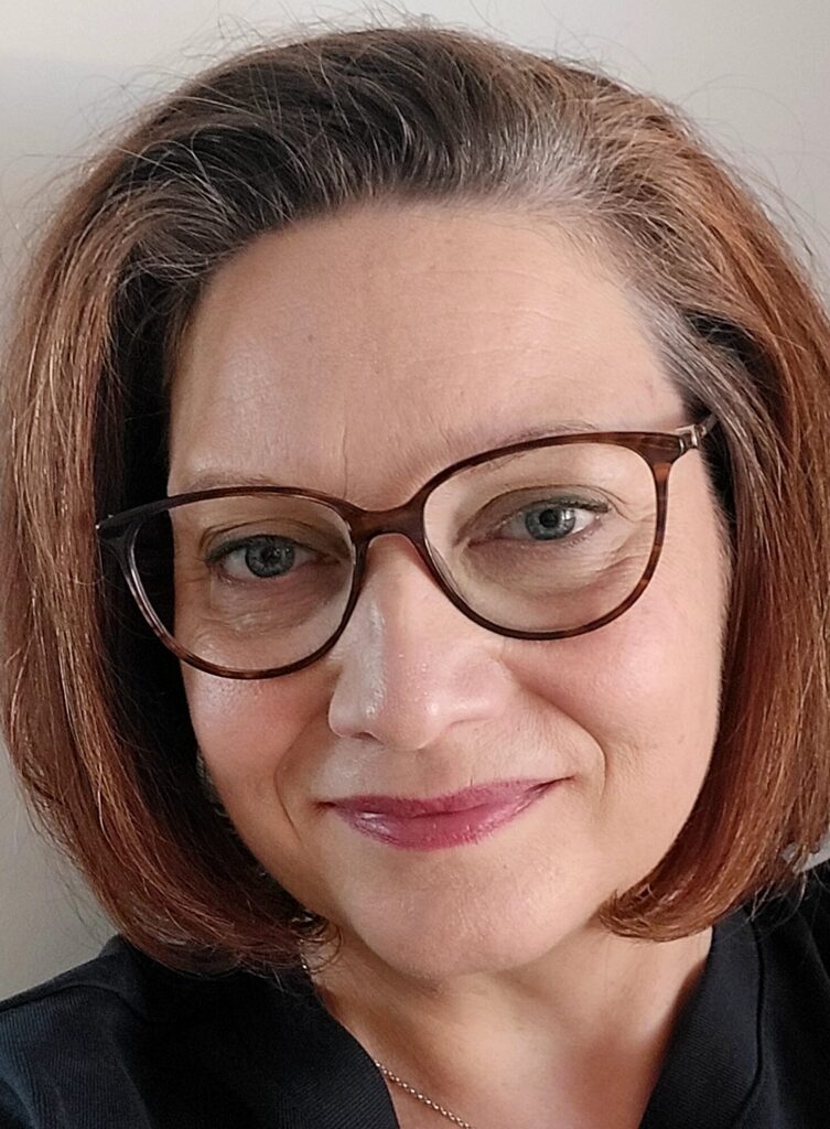 Marke Aho, ruskeat hiukset, silmälasit, katse kameraan.