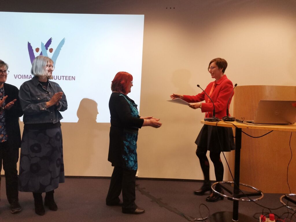 Ulla Salminen vastaanottaa Katja Borodulinilta kunniakirjan, vieressä muita palkinnon saaneita.