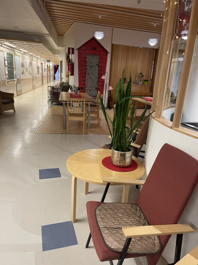 Palvelutalon sisätilaa. Etualalla tummanpunainen käsinojallinen tuoli.