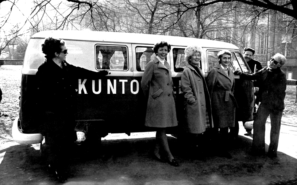Kuntokallion bussin minibussin edessä talvitakeissaan ryhmä naisia ja yksi mies. KLuva on vuodelta 1974.